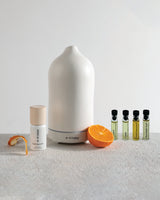 Helse Starter Kit with white stone scent diffuser next to sweet orange fruit